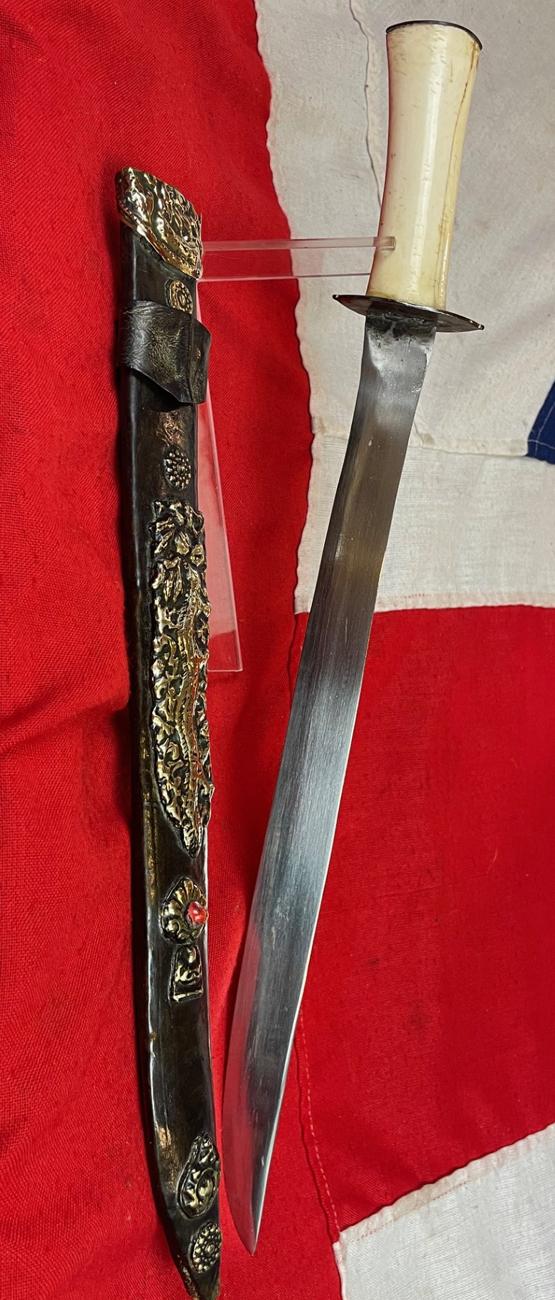 A Most Interesting & Unusual Form of Antique Tibetan Buddhist Large Dagger-Short Sword. A Dpa'dam. Decorated With Repousse Dragon and Buddha, Seated in the Padmasana Pose, in Dhyana Mudra, With Mandorla, a Coral Stone Bead Inset & Unalome Spiral Sun